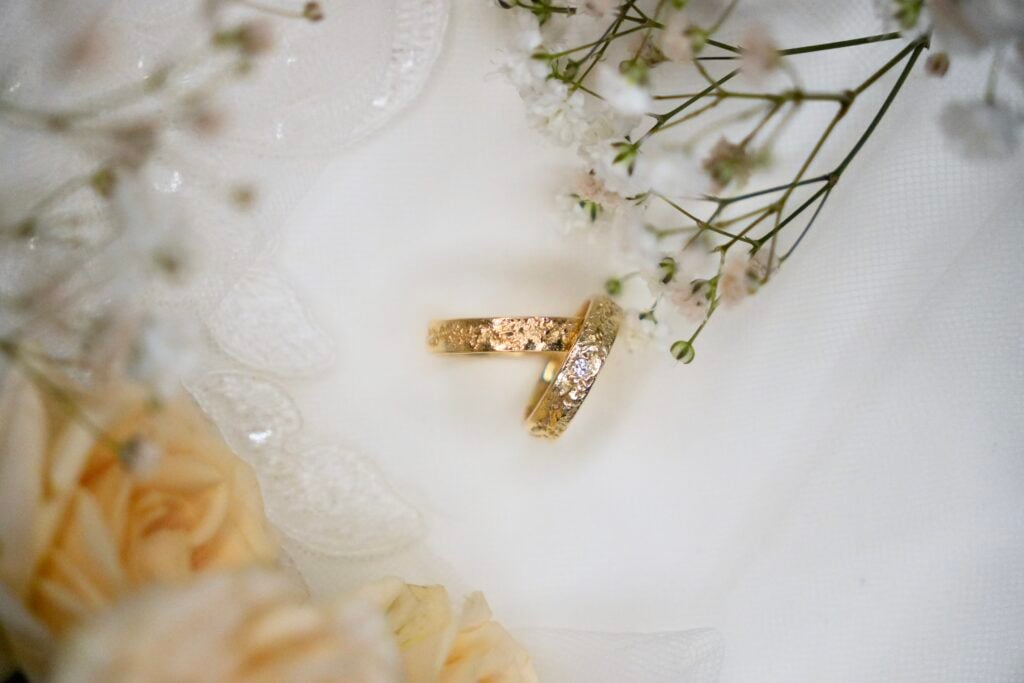 Fjæra gifteringer i gull med synlig støpekant fra sandstøp produsert i verkstedet hos Wabi Sabi