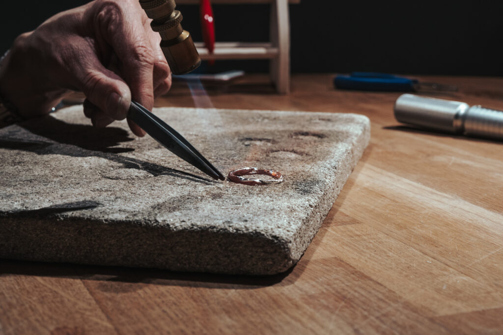 Sølvwire varmes opp og formes for hånd i verkstedet før den utvikles til en Mingle ring. Prosessen viser hvordan håndlagde smykker blir til gjennom metode og materialforståelse.