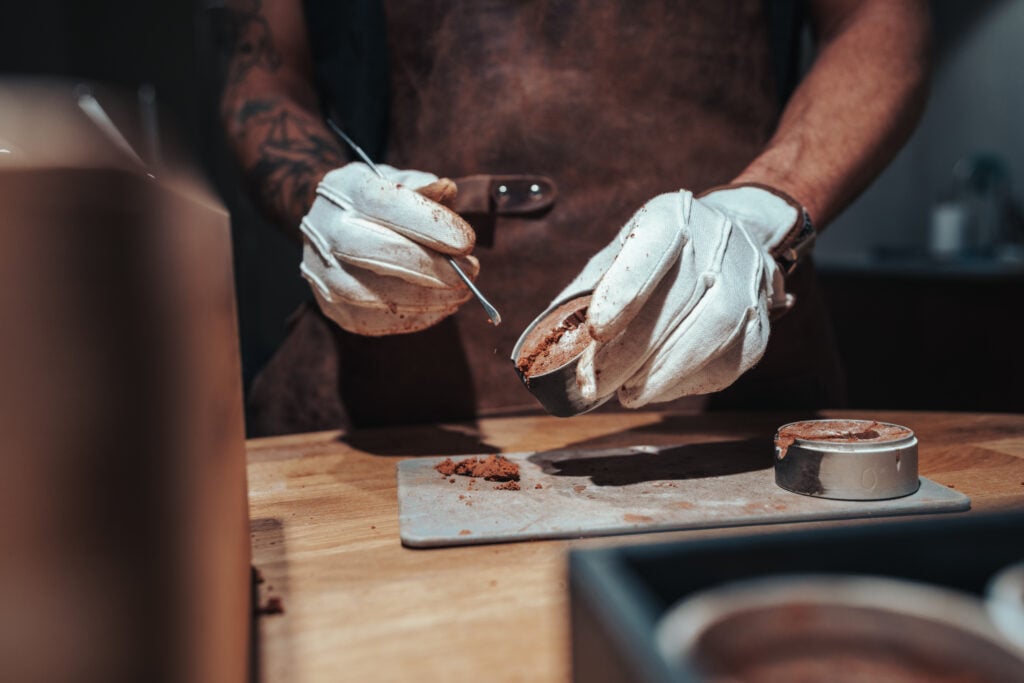 Forming a sand casting mold before gold is melted and poured into the mold to create a gold sand cast ring
