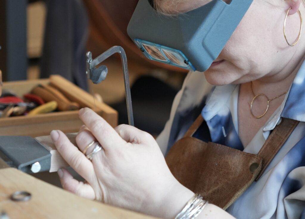 Goldsmith adjusting wedding ring for better fit in workshop